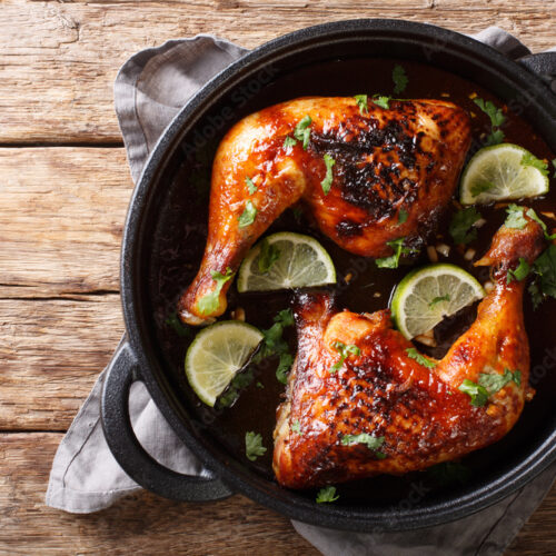 Tamarind chicken quarter leg with lime close-up in a frying pan. horizontal top view